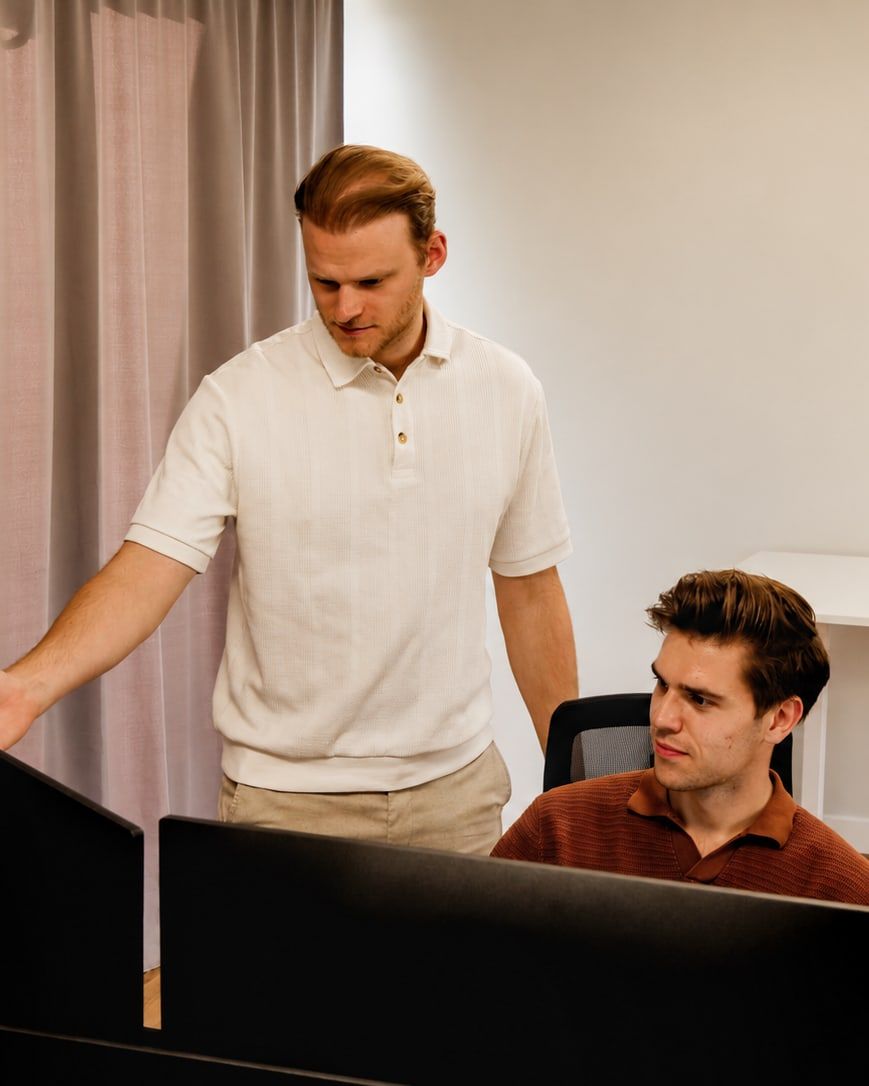 Een collega wijst iets aan op het scherm van een collega